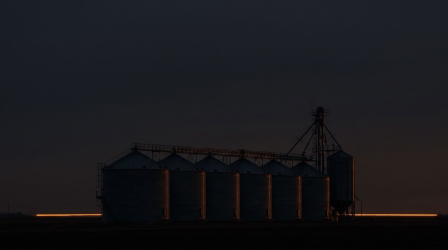 A row of steel grain bins at dusk